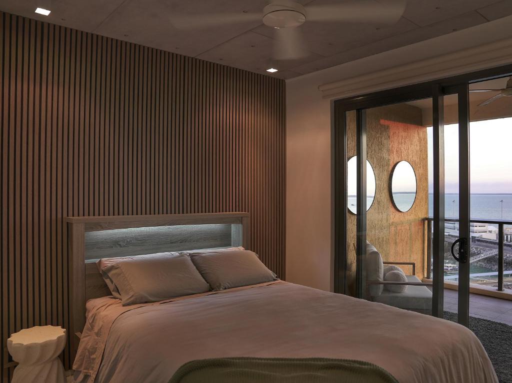 a bedroom with a bed with a view of the ocean at Penthouse-level Waterfront Apartment in Darwin