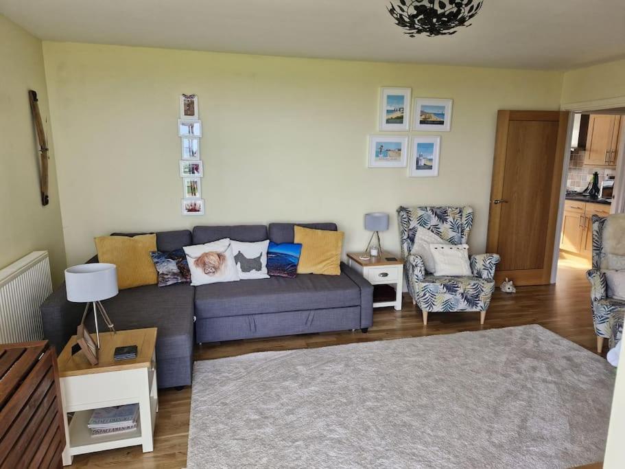 ein Wohnzimmer mit einem blauen Sofa und einem Stuhl in der Unterkunft Beachside Ground Floor Flat in Birchington