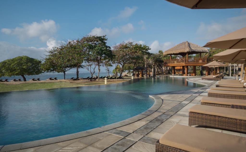 a pool at a resort with a view of the ocean at MERUSAKA Nusa Dua in Nusa Dua