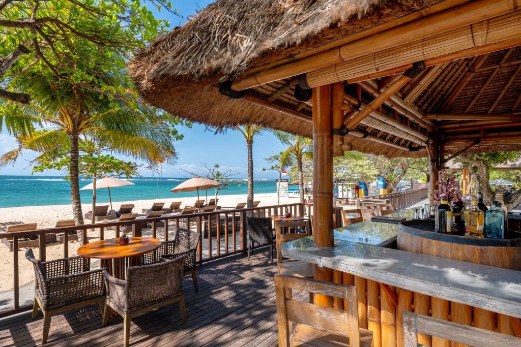 a restaurant on the beach with a table and chairs at MERUSAKA Nusa Dua in Nusa Dua