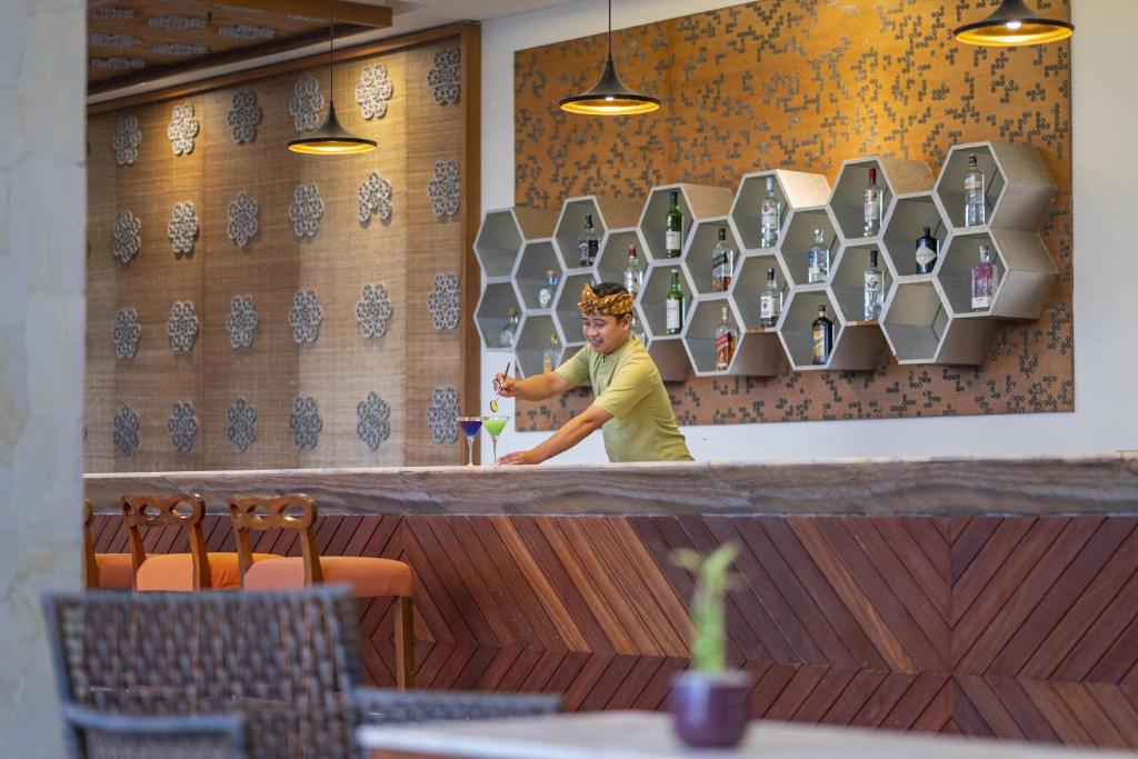 a man standing behind a counter in a restaurant at MERUSAKA Nusa Dua in Nusa Dua