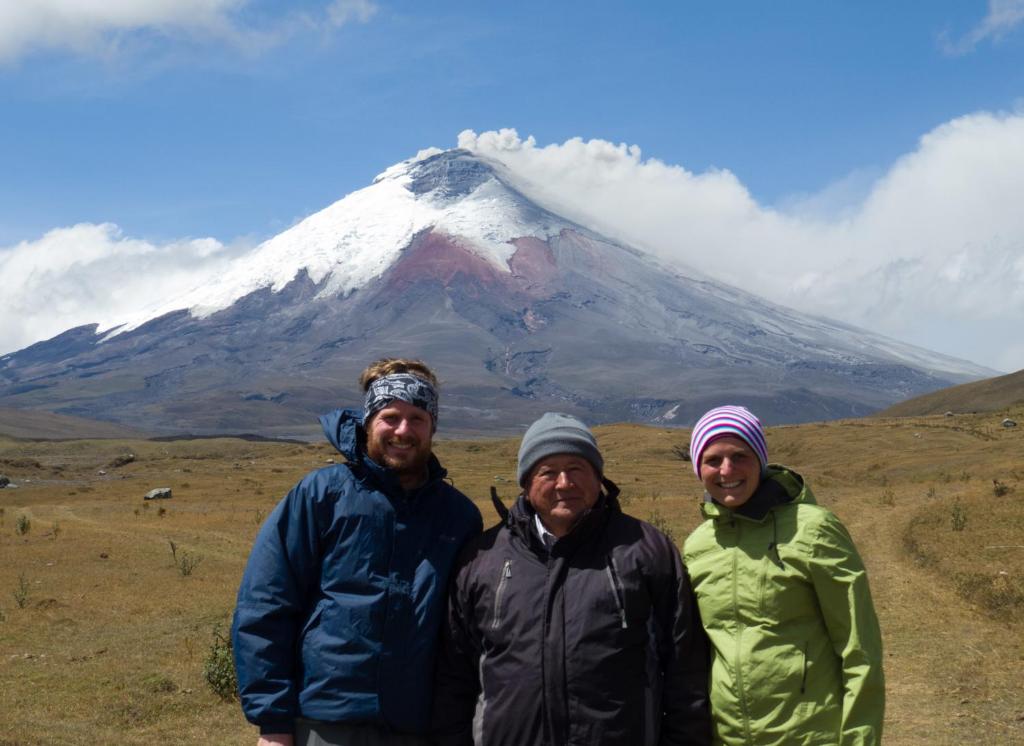 tres personas de pie frente a una montaña en Cabañas Los Volcanes, en Lasso