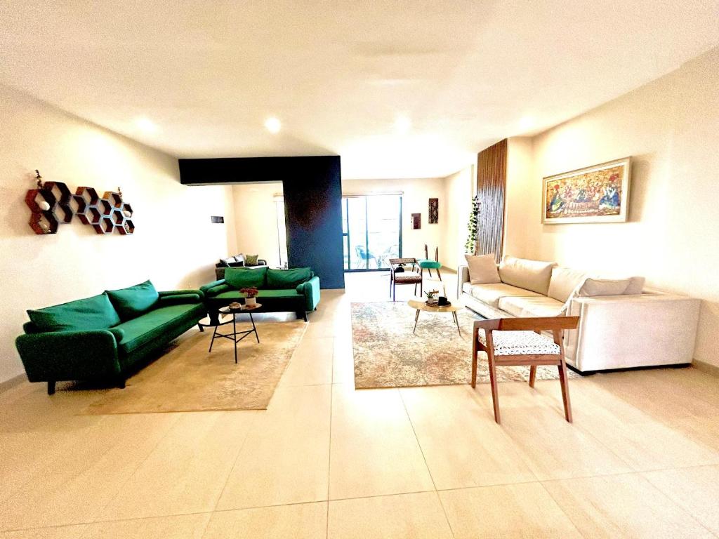 uma sala de estar com um sofá verde e cadeiras em Appartement au Almadies( piscine et salle de sport) em Dakar
