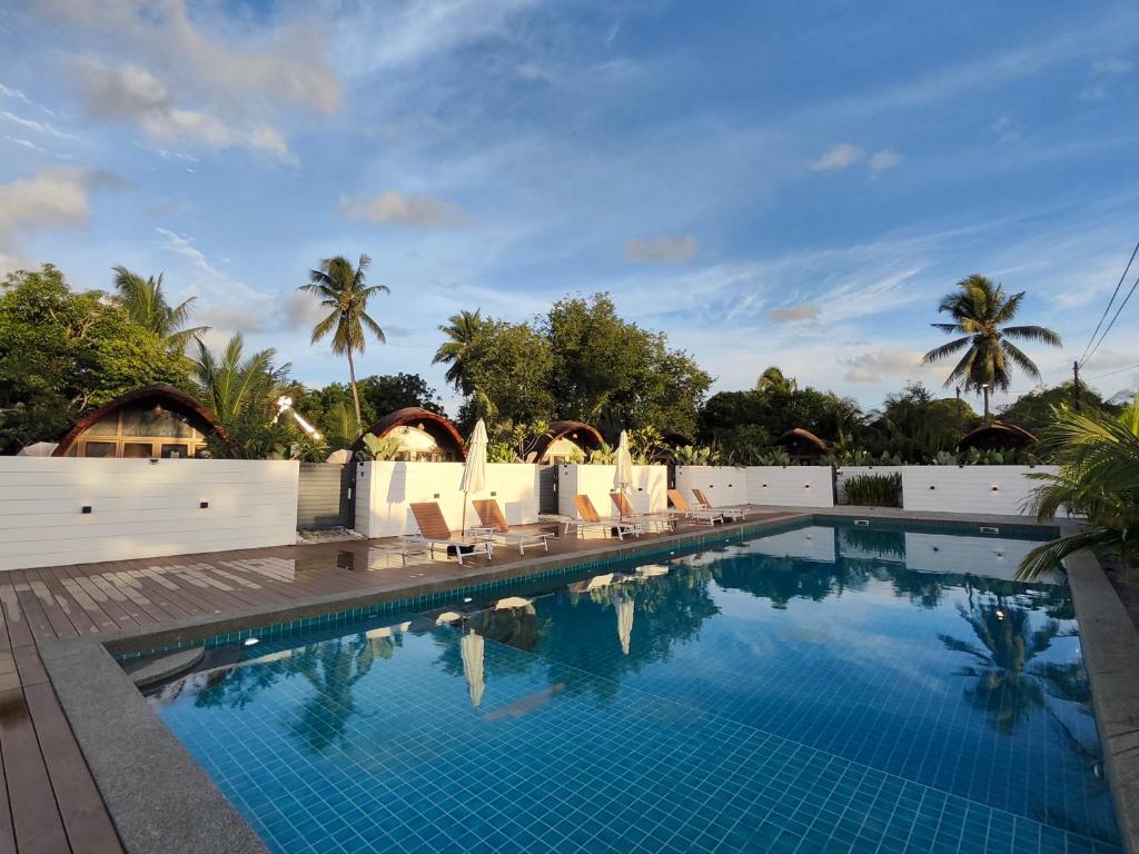uma piscina num resort com cadeiras e palmeiras em Found Mansion em Pantai Cenang