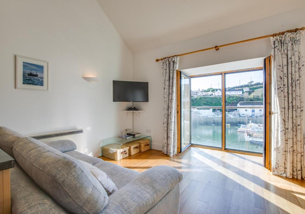 a living room with a couch and a large window at Quayside in Porthleven