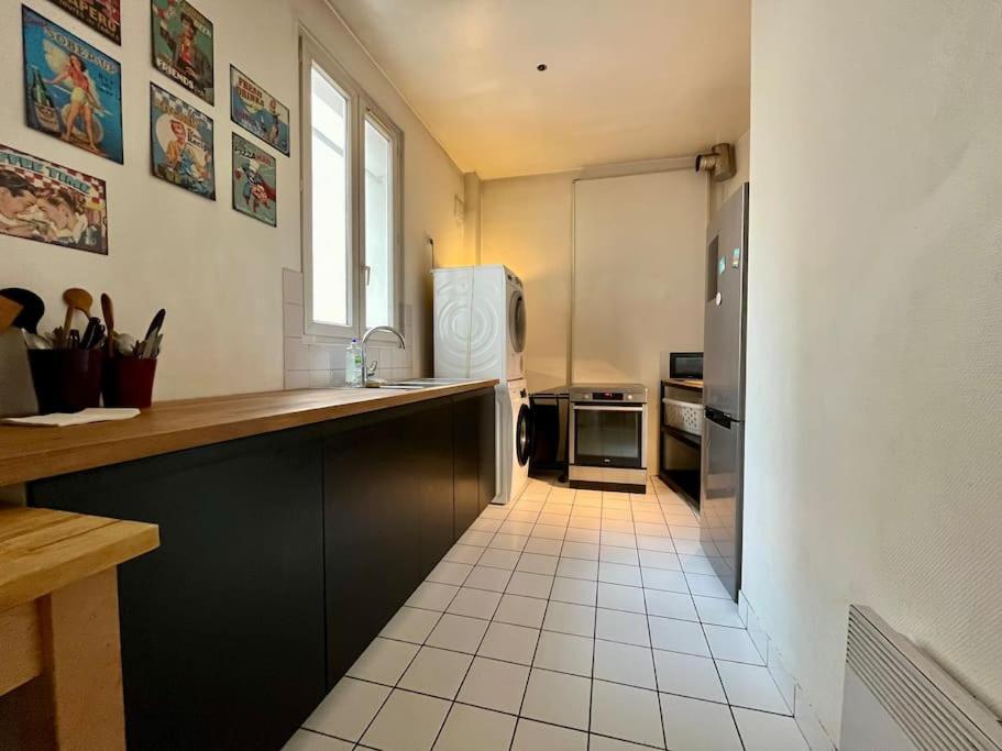 a kitchen with black cabinets and a white tile floor at Bienvenue in Montrouge