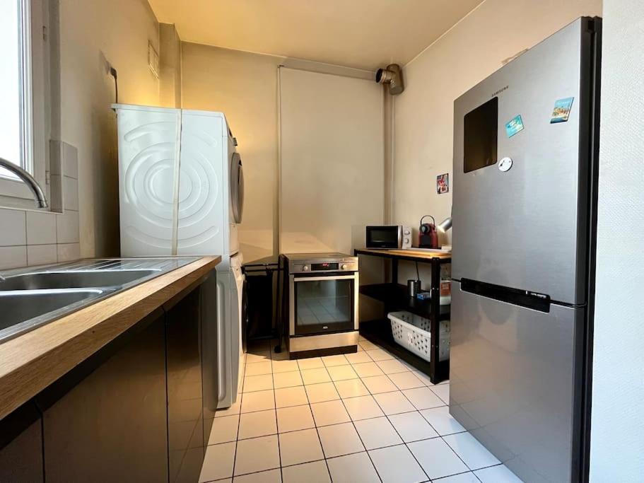 a small kitchen with a refrigerator and a sink at Bienvenue in Montrouge