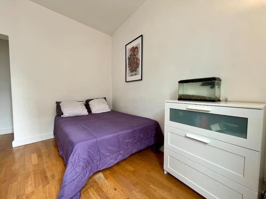 a small bedroom with a purple bed and a tv at Bienvenue in Montrouge