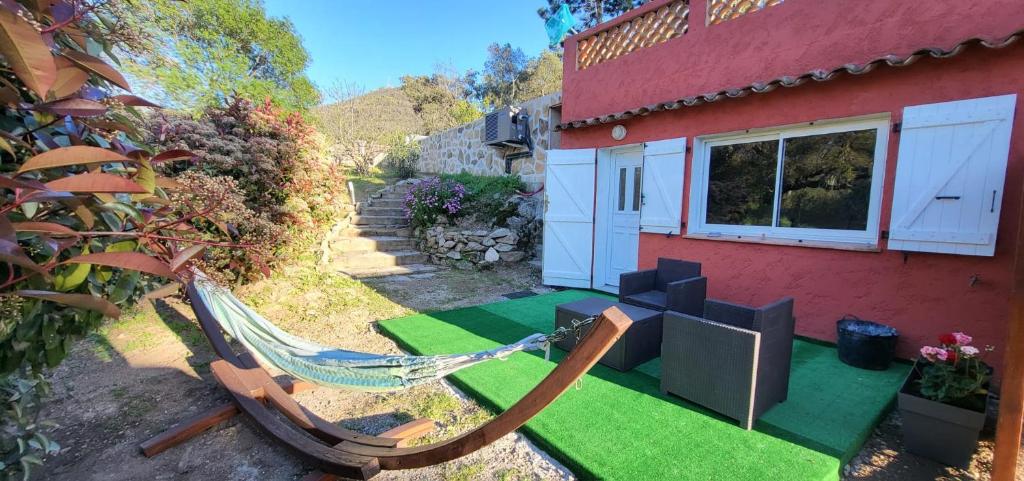 a patio with a hammock and a house at L'Aloe Vera in Plan-de-la-Tour