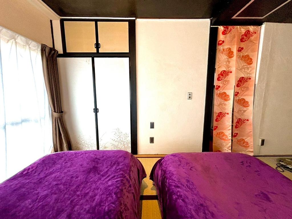 2 łóżka w pokoju z fioletową pościelą w obiekcie 酒と宿と不動産-yado- w mieście Yokosuka