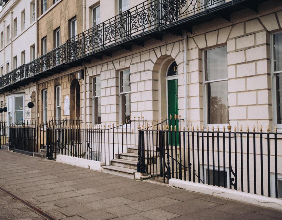 a building with a green door and a fence at Pebble View - Central Cosy with Sea-Views in Weymouth