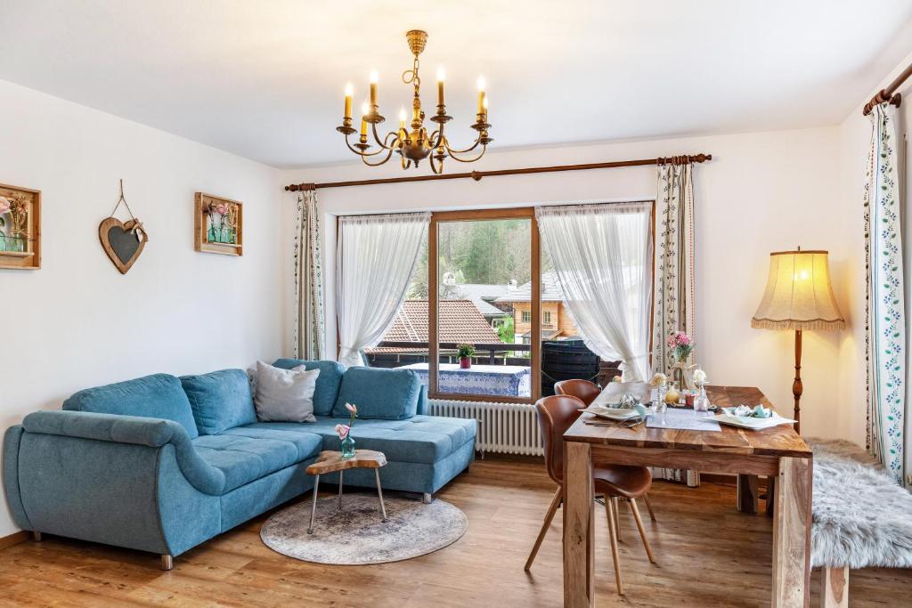 uma sala de estar com um sofá azul e uma mesa em Aschaubichl - Wohnung Alpenrose em Grainau