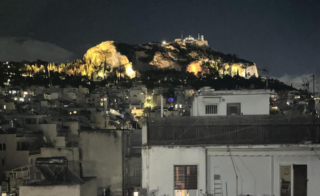 a city with a mountain in the background at night at The Best View Rent Apartment Lycabettus in Athens