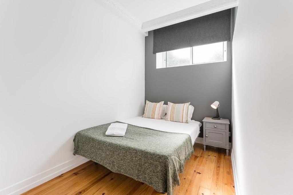 a small bedroom with a bed and a window at GuestReady - Gold Leaf in Porto