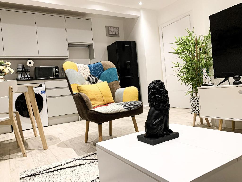 ein Wohnzimmer mit einem Stuhl und eine Küche in der Unterkunft 2 BED 1 BATH LUXURY STAY APARTMENT 20 Mins drive to Central London 10 Min Drive to Wembley Stadium Free Parking in Golders Green