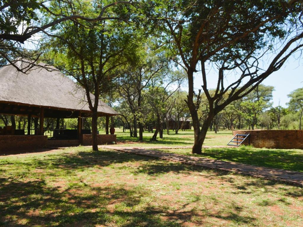 a park with a building and trees and grass at Masungulo Lodge in Modimolle