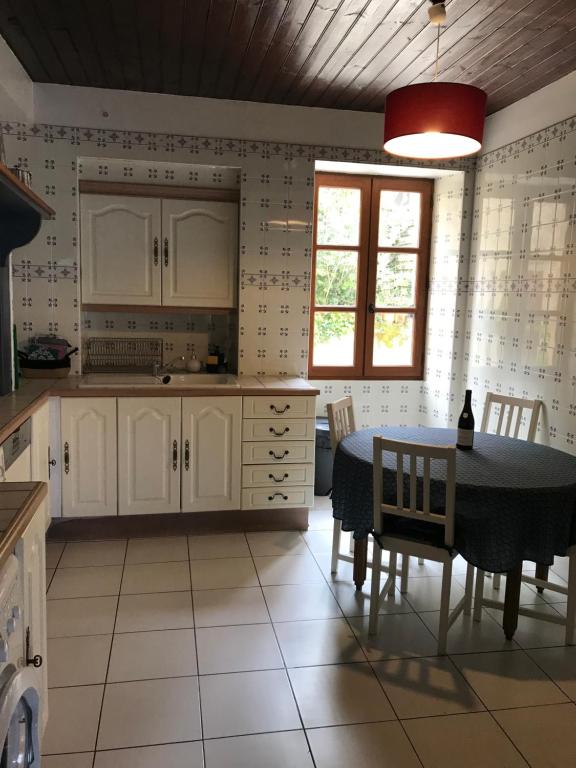 a kitchen with white cabinets and a table with chairs at villa Marguerite terrasse & garage in Belvès