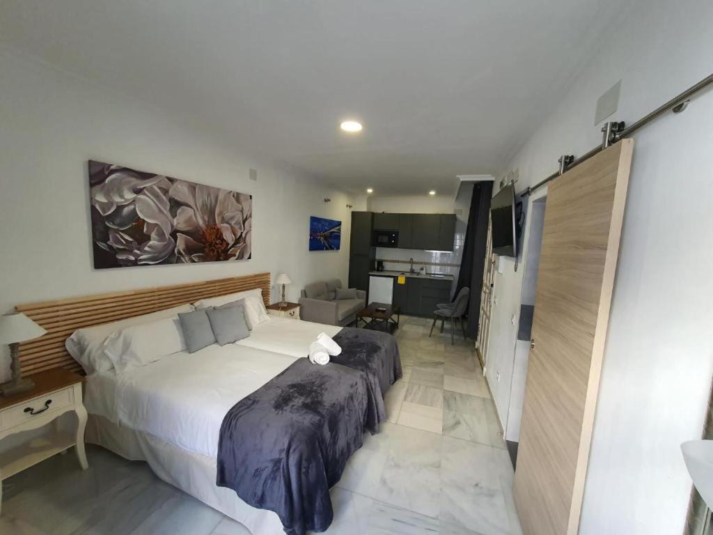 una camera con un grande letto bianco di Apartamentos Los Angeles a Siviglia