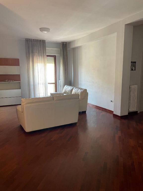 a living room with a white couch and a wooden floor at Heaven's Door in San Giovanni Rotondo