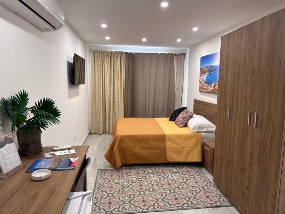 a hotel room with a bed and a desk at La Bella Guesthouse in St. Julianʼs