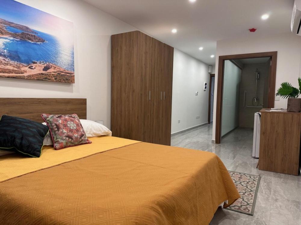 a bedroom with a large bed with a yellow blanket at La Bella Guesthouse in St. Julianʼs