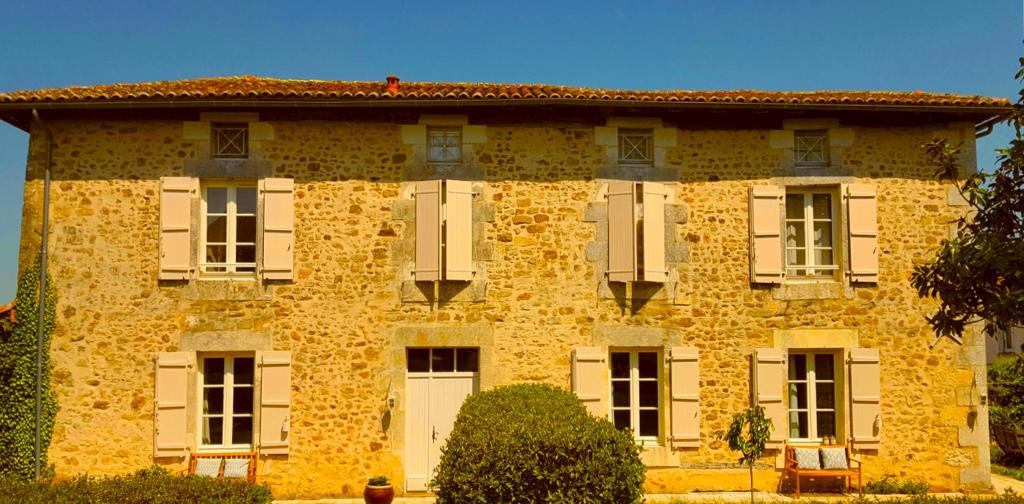 a large yellow brick building with white shutters at Domaine Charente - Holiday Home with own garden in Mazières