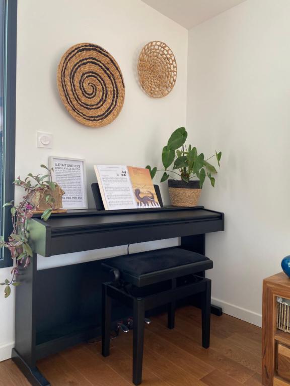 un pianoforte nero in un soggiorno con piante di Villa avec piscine 3 chambres a Foix