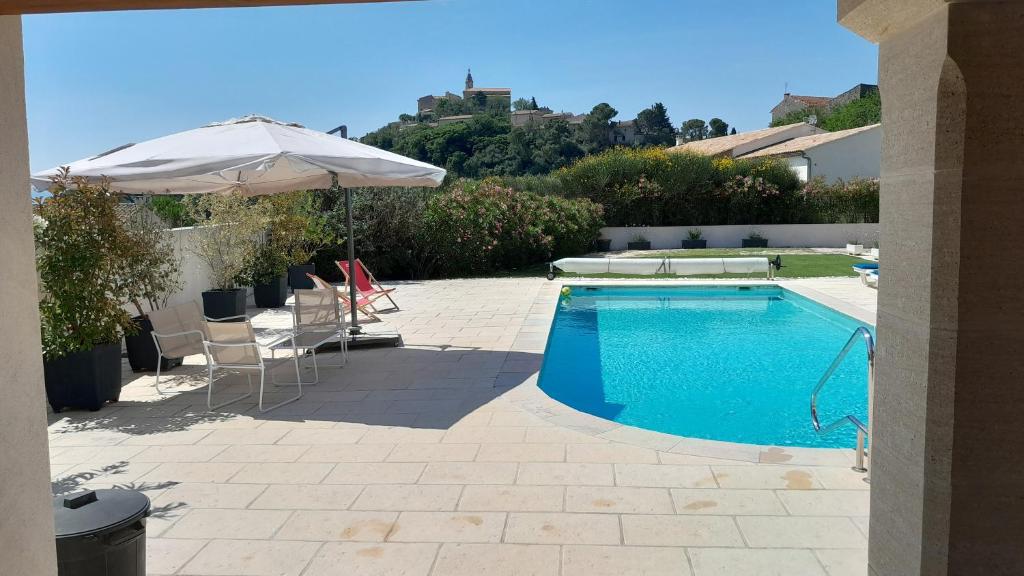 una piscina con sombrilla y sillas y una mesa con sombrilla en L'ecrin du Ventoux, en Crillon-le-Brave