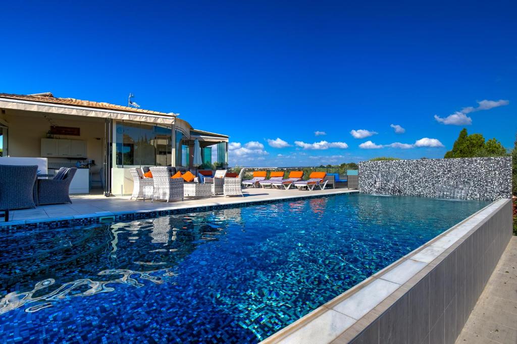 a swimming pool with chairs next to a house at 3 bedroom Villa Eleyjo with stunning private pool, Aphrodite Hills Resort in Kouklia