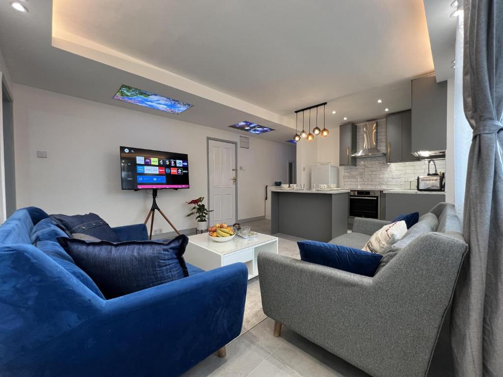 a living room with two blue couches and a kitchen at Luxury 2 Bed Apartment in Royal Sutton Coldfield in Sutton Coldfield