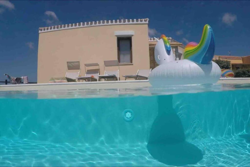 a pool with an inflatable unicorn in front of a house at Villa Cristallina Piscina privata, Wi-Fi & Netflix in Stintino