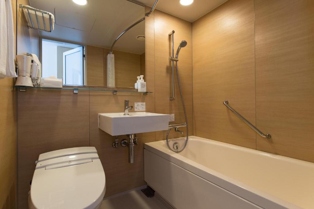 a bathroom with a toilet and a sink and a tub at JR Kyushu Hotel Blossom Shinjuku in Tokyo