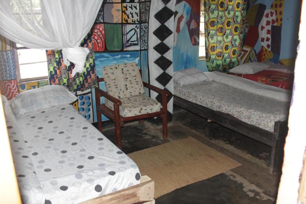 ein Zimmer mit 2 Betten und einem Stuhl darin in der Unterkunft Room in BB - Red Rocks Rwanda - Triple Room in Nyakinama