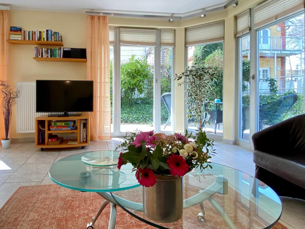 ein Wohnzimmer mit einem Glastisch mit einer Blumenvase in der Unterkunft Residenz Bleichröder - Ferienwohnung 14 in Heringsdorf