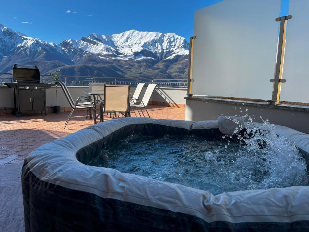 una bañera de hidromasaje en un patio con montañas al fondo en Jacuzzi mountain view appartment, en Cassina Valsassina