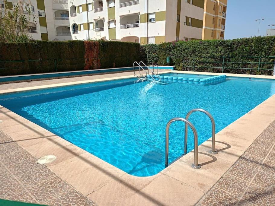 a swimming pool with blue water in a building at Apartamento Jardin II in Playa de Gandia