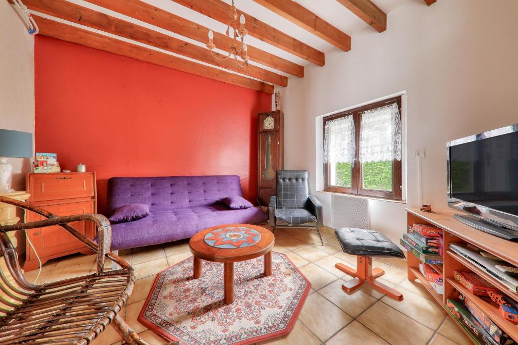een woonkamer met een paarse bank en een tv bij Maison avec jardin pour 6 entre golf et plage in Saint-Gildas-de-Rhuys