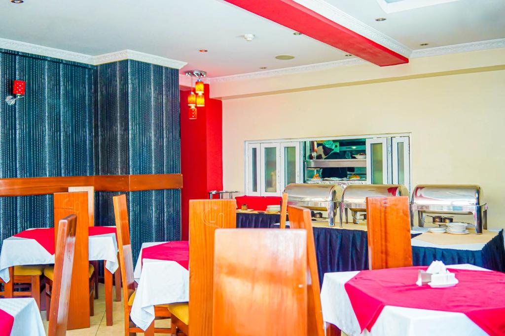 a dining room with tables and chairs and red walls at After 40 Hotel in Nairobi
