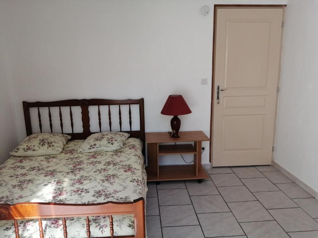 een slaapkamer met een bed en een tafel met een lamp bij Appartement 2 pièces, équipé avec clim et parking. in Béziers