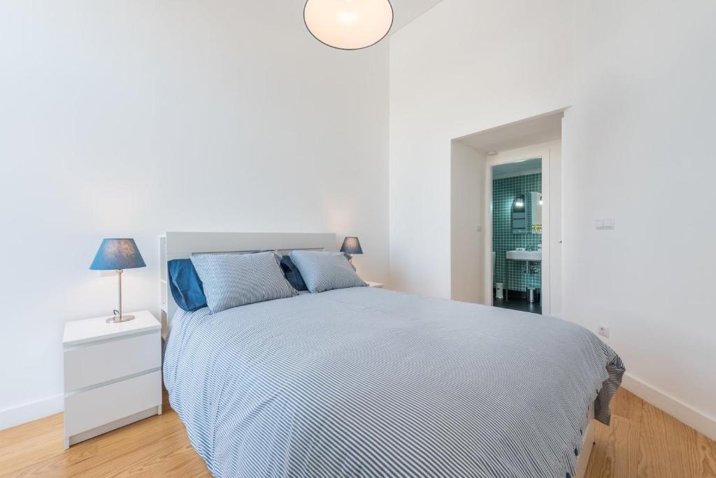 - une chambre blanche avec un grand lit et des oreillers bleus dans l'établissement GuestReady - Estadia moderna no centro do Porto, à Porto