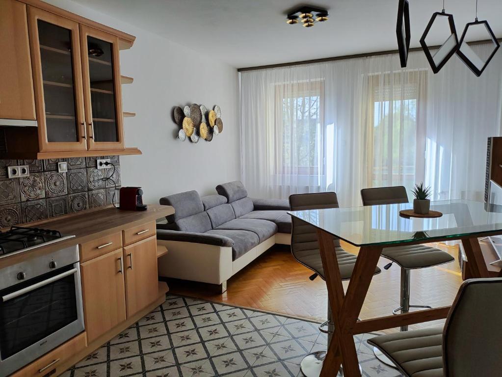 eine Küche und ein Wohnzimmer mit einem Tisch und einem Sofa in der Unterkunft Júlia Apartman Kaposvár*** in Kaposvár