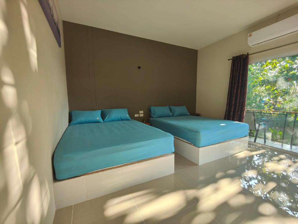 1 Schlafzimmer mit 2 Betten und einem Fenster in der Unterkunft ริมธารริเวอร์เพลส in Surat Thani