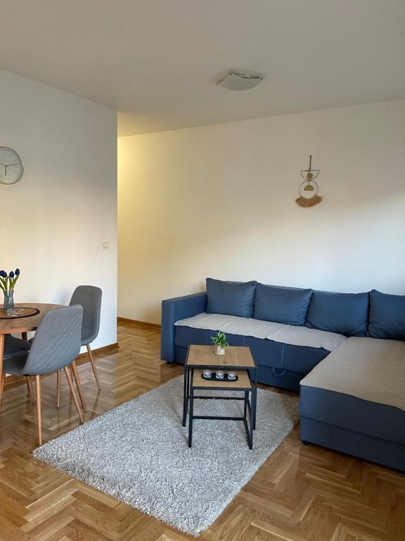 een woonkamer met een blauwe bank en een tafel bij Cvetanov trg LUX 4 in Belgrado
