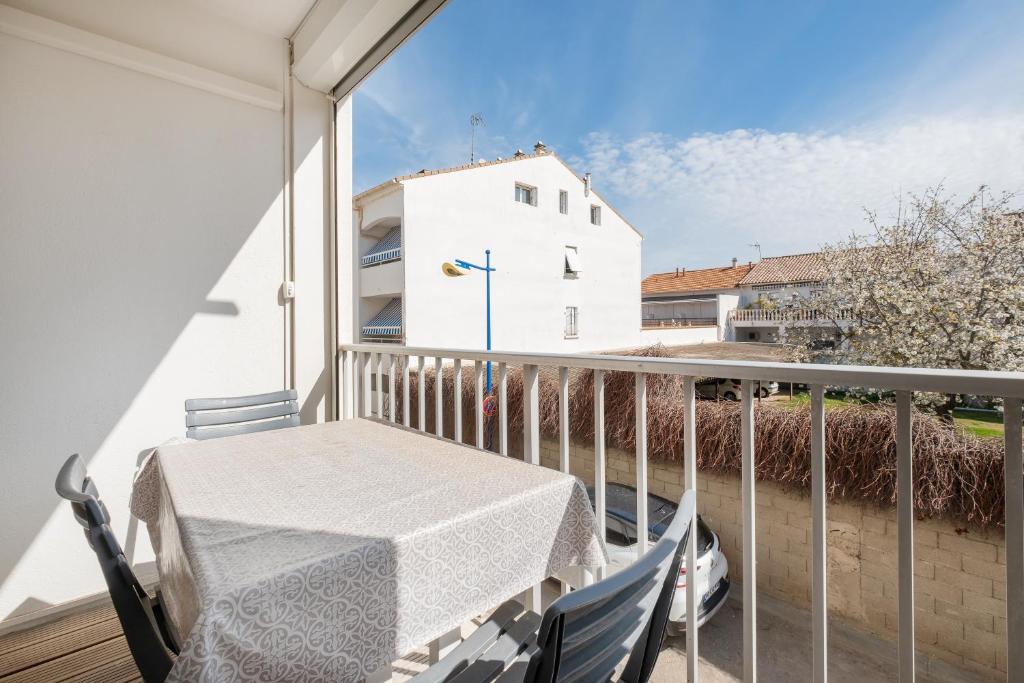 - un balcon avec une table et un bâtiment blanc dans l'établissement AS9405- P2 Centre ville- clim et garage, au Grau-du-Roi
