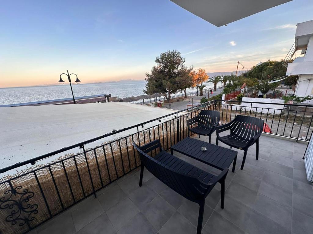 a balcony with chairs and a view of the ocean at Agioi Theodoroi Beachview Chic Modern Apt in Agioi Theodoroi