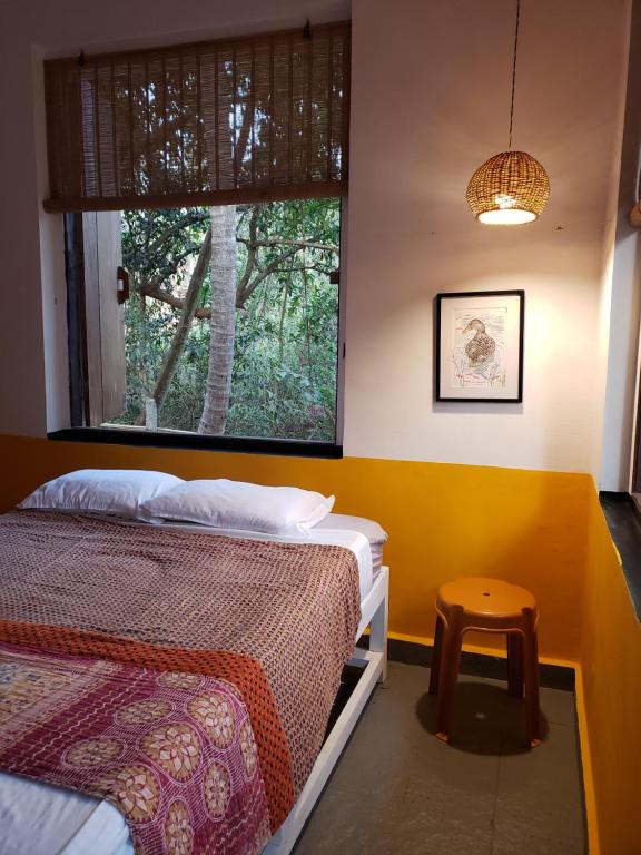 a bedroom with two beds and a stool next to a window at Laxmi Happy Home in Querim Goa in Querim