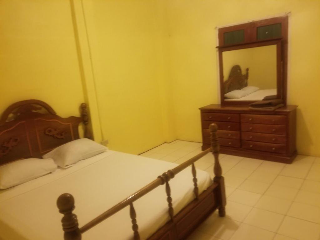 a bedroom with a bed and a dresser with a mirror at Alicia's lodge in Port-of-Spain