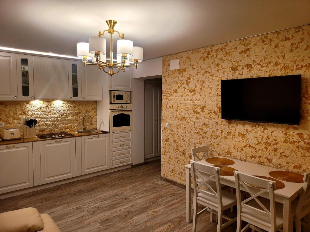 Il comprend une cuisine avec une table et une télévision murale. dans l'établissement R&R Apartament, à Ocna-Mureşului