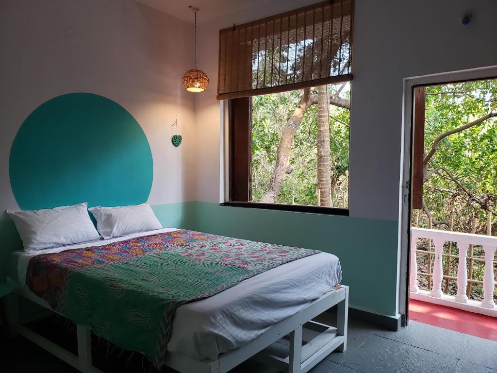 a bedroom with a bed with a green headboard and two windows at Laxmi Happy Home in Querim Goa in Querim
