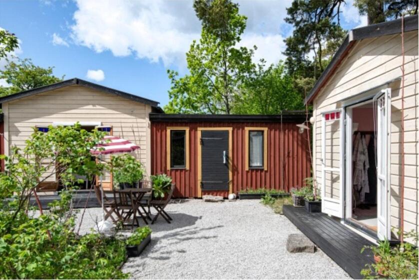 un cottage con patio, tavolo e ombrellone di Mysig tomt med stugor i Rute a Lärbro